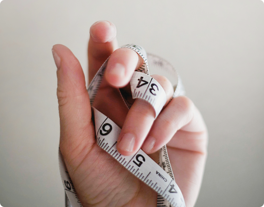 mão feminina segurando fita de medida