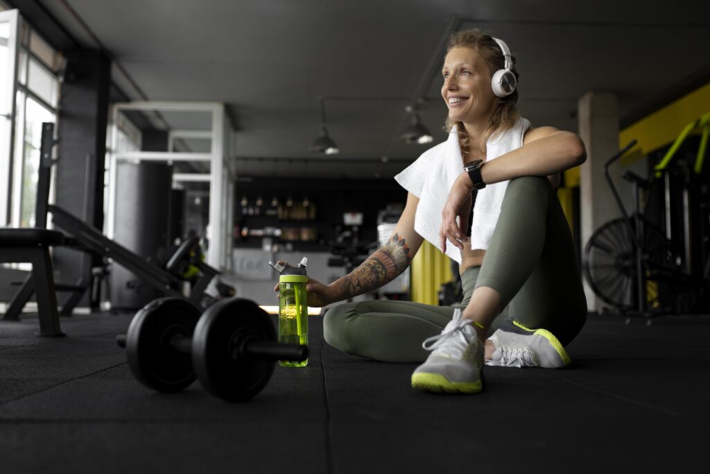 mulher feliz sentada ao chão pós-treino da academia